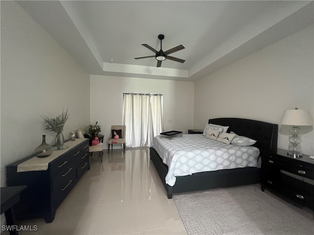 bedroom with a raised ceiling, light tile patterned flooring, and ceiling fan