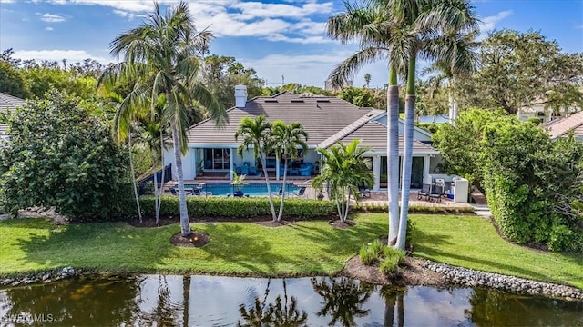 rear view of house featuring a yard, a water view, and a patio