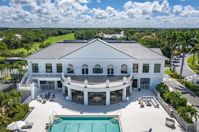 back of property featuring a patio and a fenced in pool