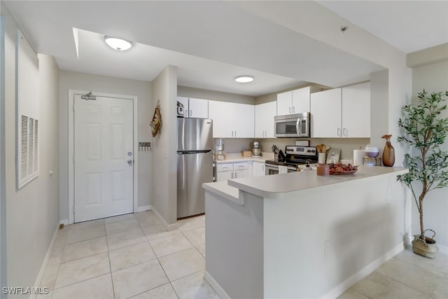 kitchen with appliances with stainless steel finishes, kitchen peninsula, white cabinets, and light tile patterned floors