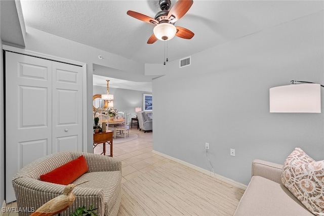 sitting room with a textured ceiling, light tile patterned floors, and ceiling fan