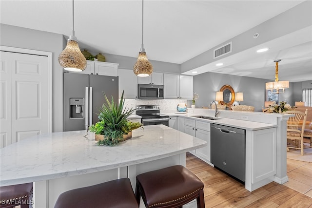 kitchen with pendant lighting, a kitchen breakfast bar, stainless steel appliances, and light wood-type flooring