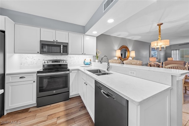 kitchen featuring kitchen peninsula, hanging light fixtures, white cabinetry, light hardwood / wood-style flooring, and stainless steel appliances