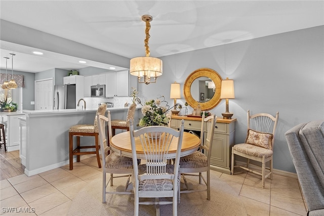 tiled dining space featuring sink and an inviting chandelier