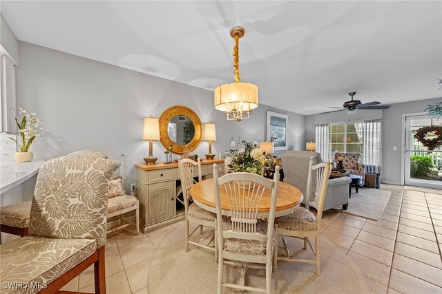 dining area with light tile patterned flooring and ceiling fan with notable chandelier