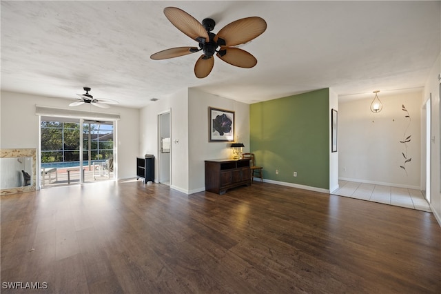 unfurnished living room featuring dark wood-type flooring and ceiling fan