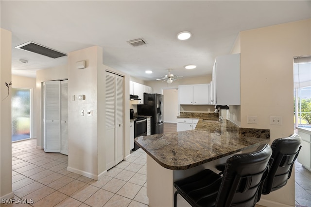 kitchen featuring kitchen peninsula, white cabinets, light tile patterned floors, a kitchen breakfast bar, and stainless steel fridge with ice dispenser