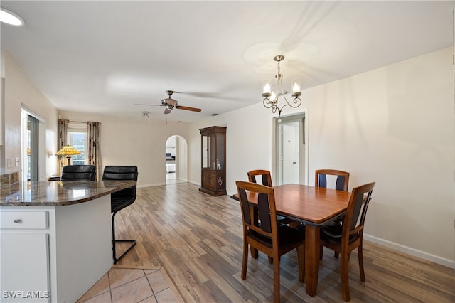 dining area with light hardwood / wood-style flooring and ceiling fan with notable chandelier