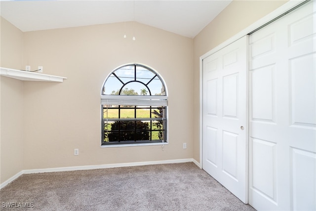 unfurnished bedroom featuring light carpet, a closet, and vaulted ceiling