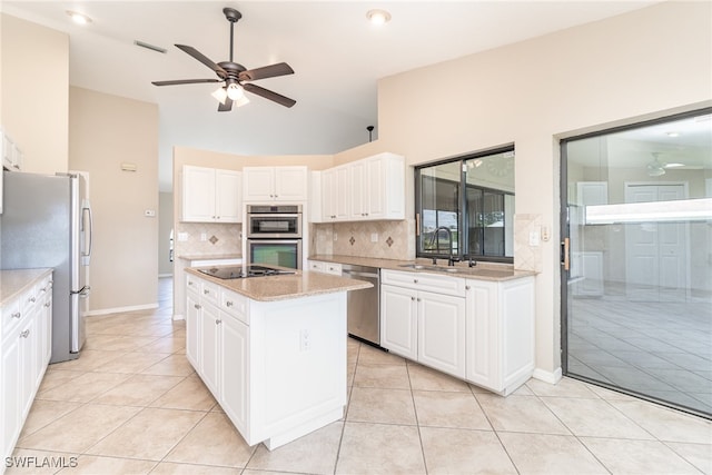 kitchen with appliances with stainless steel finishes, sink, a kitchen island, and white cabinets