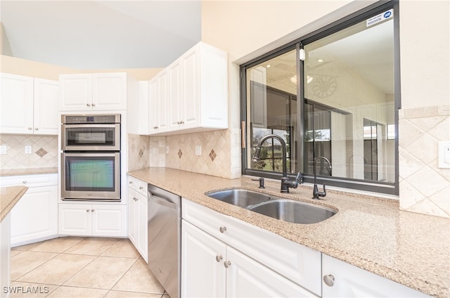 kitchen with white cabinets, light tile patterned floors, vaulted ceiling, sink, and stainless steel appliances