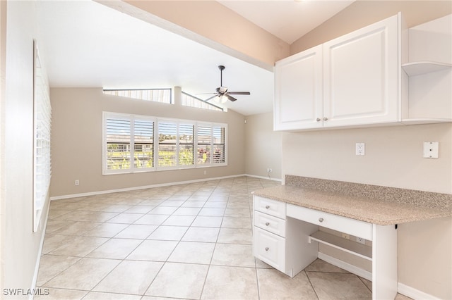 unfurnished office with lofted ceiling, built in desk, light tile patterned floors, and ceiling fan