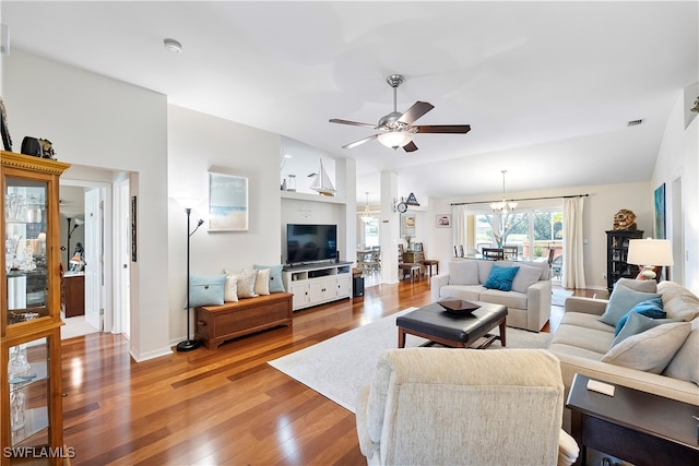 living room with hardwood / wood-style flooring, lofted ceiling, and ceiling fan with notable chandelier