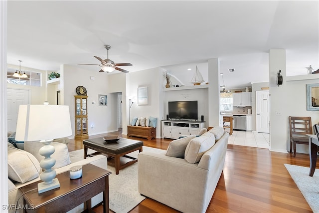 living room with light hardwood / wood-style flooring and ceiling fan with notable chandelier