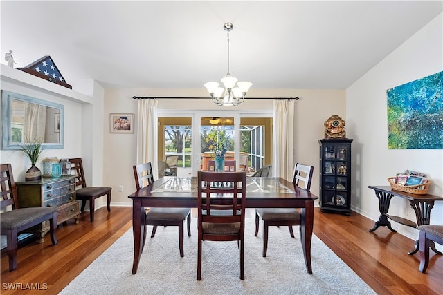 dining room featuring hardwood / wood-style flooring, vaulted ceiling, and a chandelier