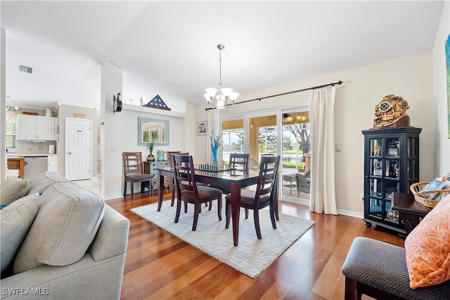 dining area with a notable chandelier, dark hardwood / wood-style floors, and vaulted ceiling