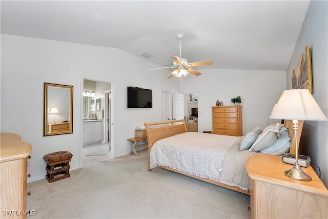 bedroom with light carpet, connected bathroom, vaulted ceiling, and ceiling fan