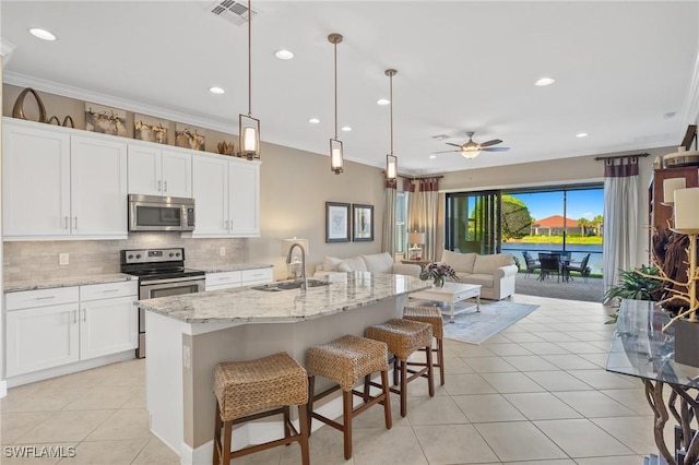 kitchen with sink, stainless steel appliances, white cabinets, and a center island with sink