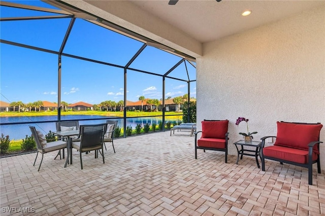 view of patio with glass enclosure and a water view