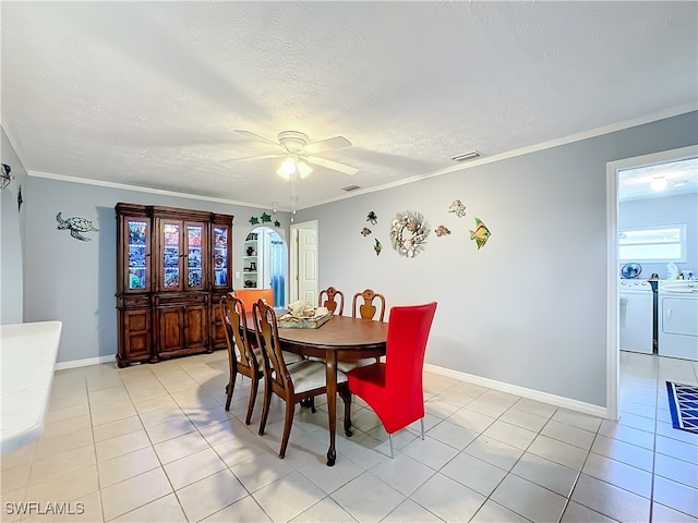 dining room featuring ceiling fan, independent washer and dryer, a textured ceiling, ornamental molding, and light tile patterned flooring