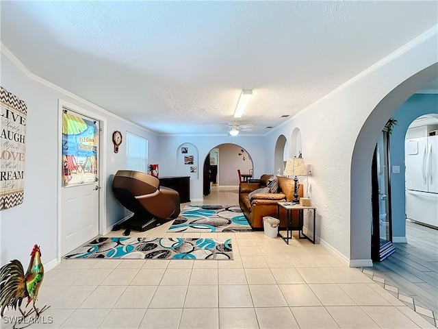 interior space with light tile patterned floors, a textured ceiling, ceiling fan, and ornamental molding