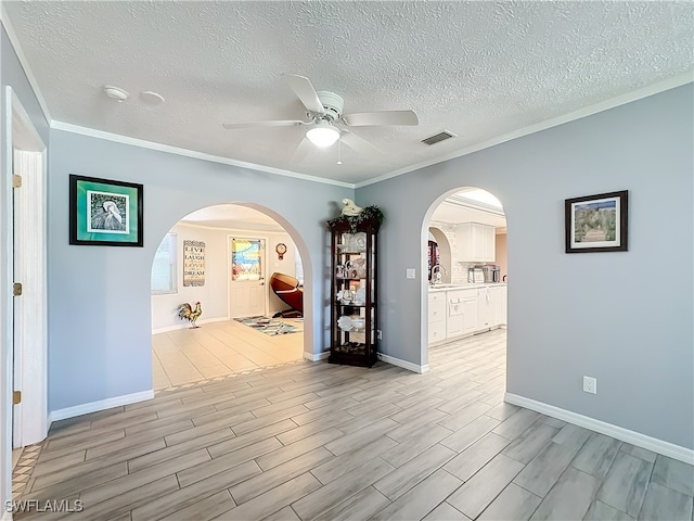 empty room with a textured ceiling, ceiling fan, crown molding, and sink