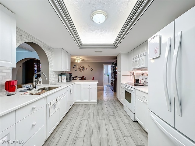 kitchen featuring kitchen peninsula, tasteful backsplash, white appliances, sink, and white cabinetry