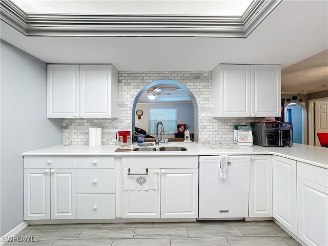 kitchen featuring white dishwasher, backsplash, white cabinetry, and sink