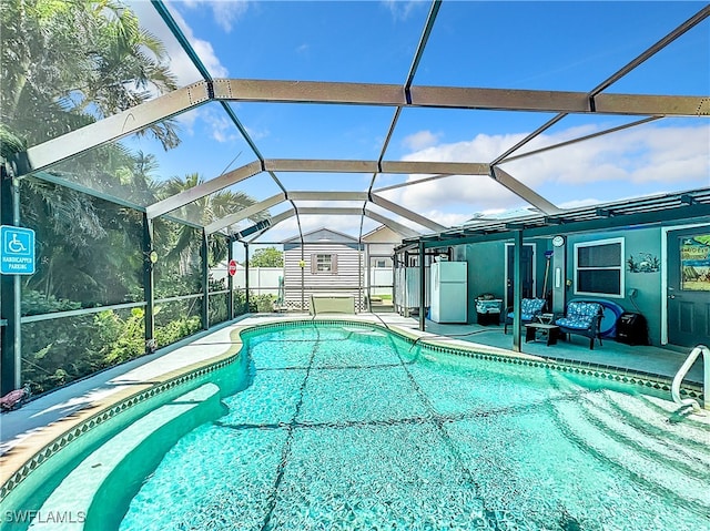 view of swimming pool with glass enclosure, a patio area, and a shed