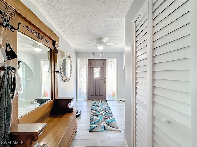 foyer entrance with a textured ceiling, ceiling fan, and ornamental molding