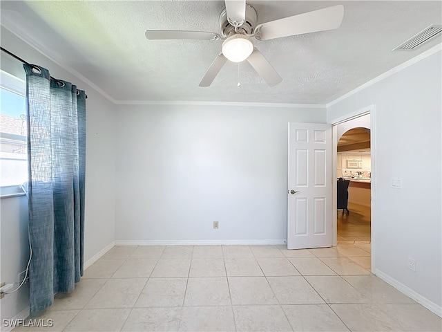 tiled empty room featuring ceiling fan and ornamental molding