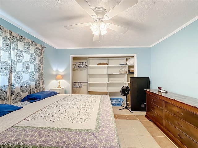 bedroom with ceiling fan, light tile patterned flooring, crown molding, and a closet