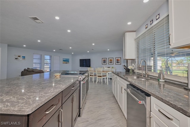 kitchen with white cabinetry, dark stone countertops, sink, dark brown cabinetry, and stainless steel appliances