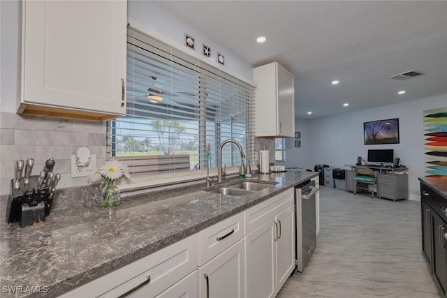 kitchen featuring backsplash, dark stone counters, sink, stainless steel dishwasher, and white cabinets