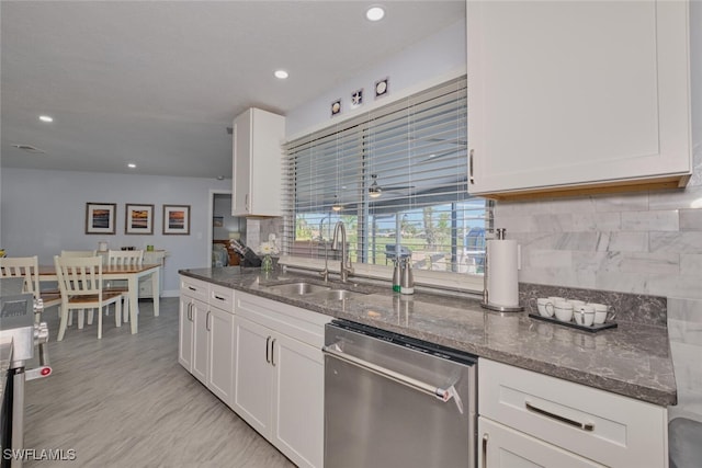 kitchen with sink, dishwasher, white cabinetry, and dark stone counters