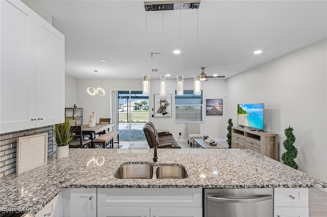 kitchen with white cabinets, decorative light fixtures, sink, and light stone counters