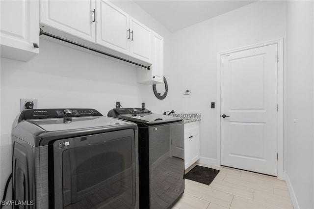 clothes washing area featuring washing machine and dryer and cabinets