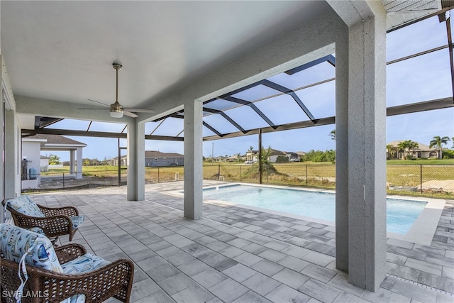 view of swimming pool with a patio, ceiling fan, and glass enclosure