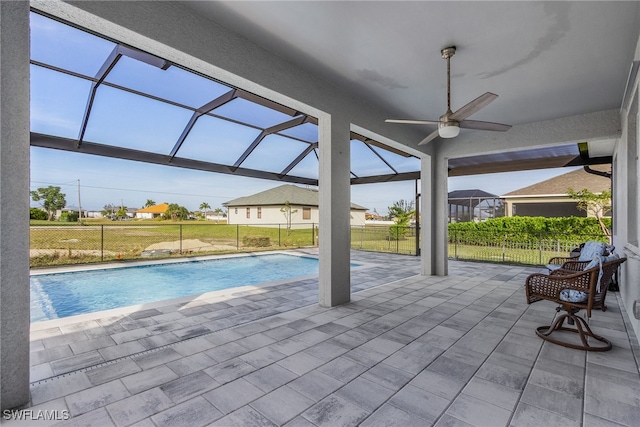 view of pool featuring a patio, ceiling fan, a lawn, and glass enclosure