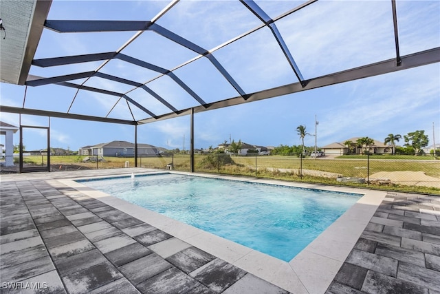 view of swimming pool with a yard, a patio area, and glass enclosure