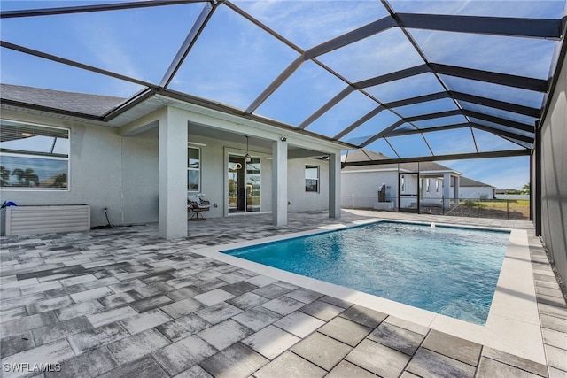 view of swimming pool featuring a patio, glass enclosure, and ceiling fan