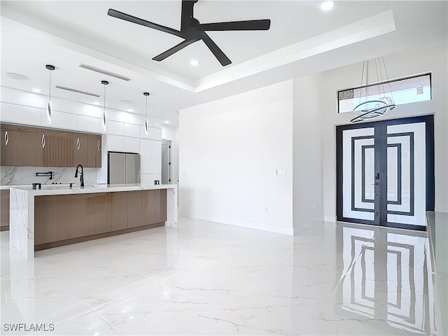 kitchen featuring pendant lighting, french doors, a raised ceiling, ceiling fan, and stainless steel fridge