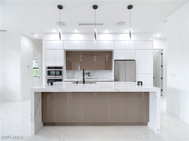 kitchen featuring white cabinets, decorative light fixtures, stainless steel appliances, and a large island with sink