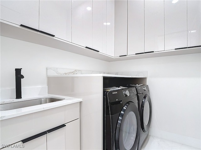 clothes washing area with cabinets, separate washer and dryer, and sink