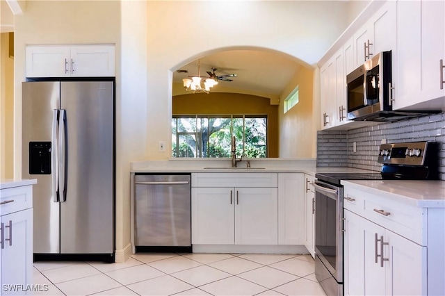 8771 Ibis Cove Cir, Naples, FL 34119 - kitchen with light countertops, vaulted ceiling, white cabinets, stainless steel appliances, and a sink