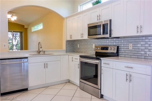 kitchen with sink, tasteful backsplash, vaulted ceiling, appliances with stainless steel finishes, and white cabinets