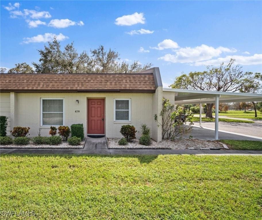 6300 S Pointe Blvd Unit 478, Fort Myers, FL 33919 - view of front of home with a shingled roof, a front lawn, concrete driveway, and a carport