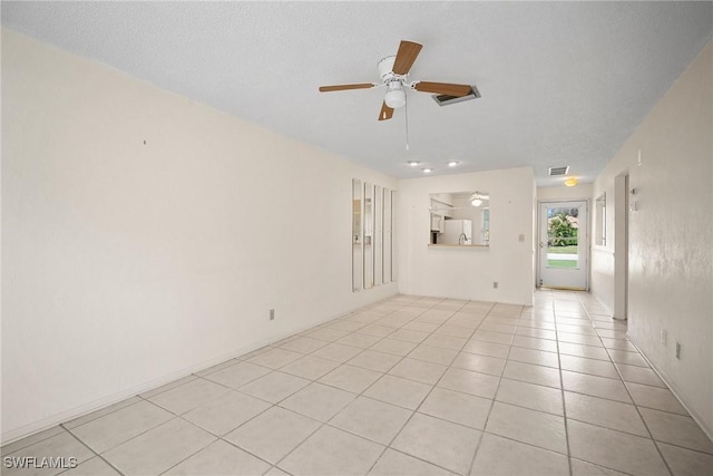 tiled spare room with ceiling fan and a textured ceiling