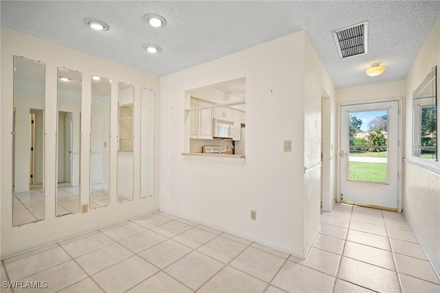 interior space with light tile patterned floors and a textured ceiling