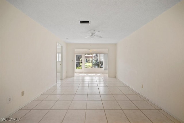 spare room featuring ceiling fan, light tile patterned floors, and a textured ceiling